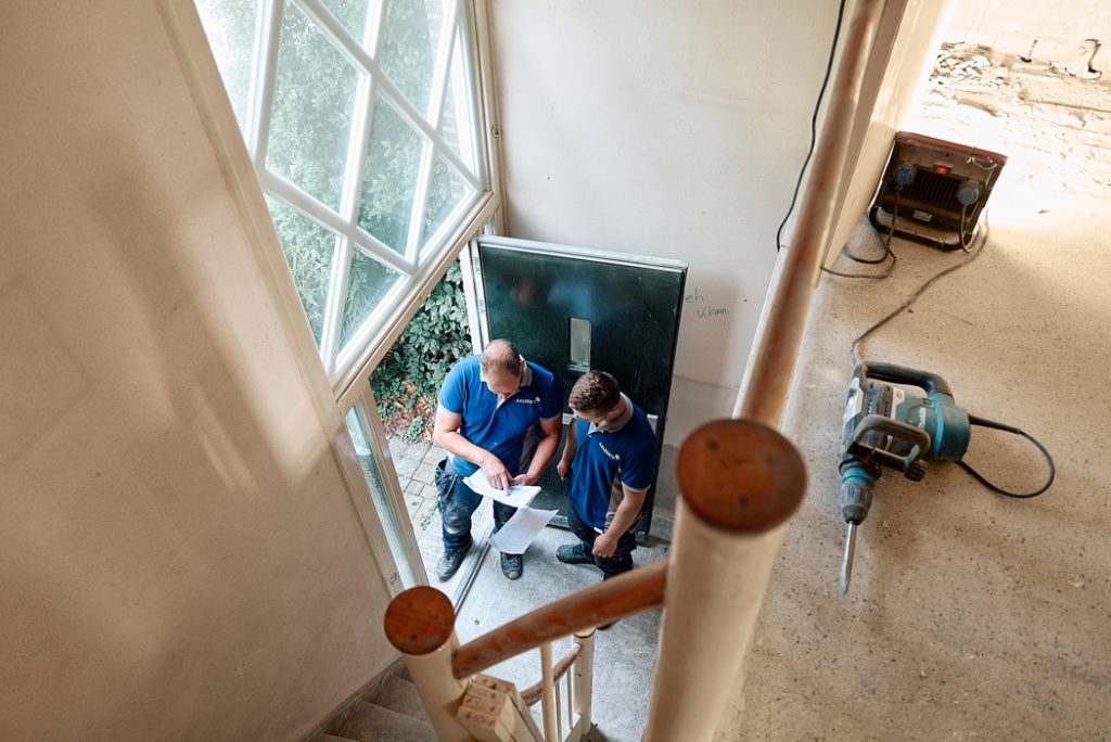 Collega's Ron en Lorenzo in de hal van de mutatie woning aan het overleggen.
