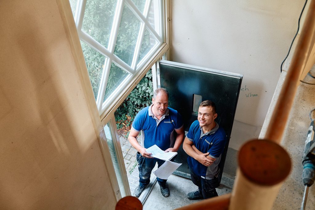 Collega's Ron en Lorenzo in de hal aan het overleggen.